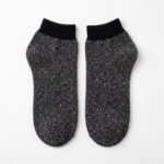 Black speckled ankle socks with ribbed cuffs displayed on a white background
