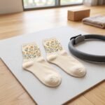 Pair of cream ankle socks with yellow floral and green leaf pattern on a white background