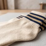 Pair of cream ankle socks with navy blue and gold striped cuffs