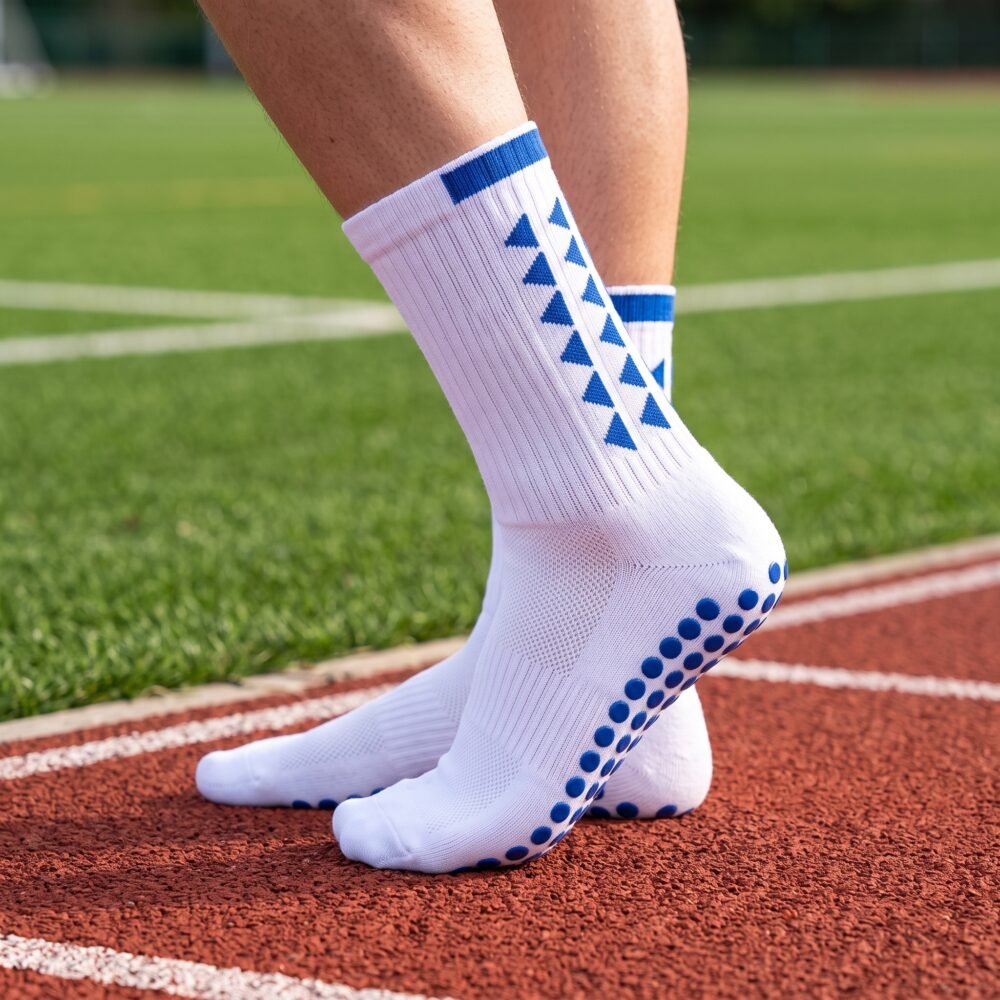 White grip socks with blue non-slip traction dots worn on a running track