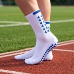 White grip socks with blue non-slip traction dots worn on a running track
