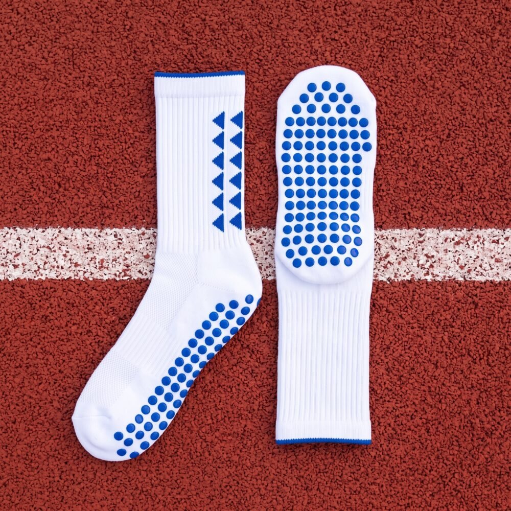 White grip socks with blue non-slip traction dots worn on a running track