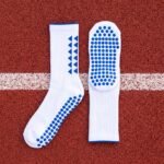 White grip socks with blue non-slip traction dots worn on a running track