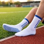 White grip socks with blue non-slip traction dots worn on a running track