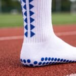 White grip socks with blue non-slip traction dots worn on a running track