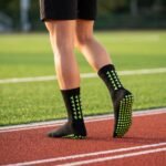 Black grip socks with lime green non-slip traction dots worn on a running track