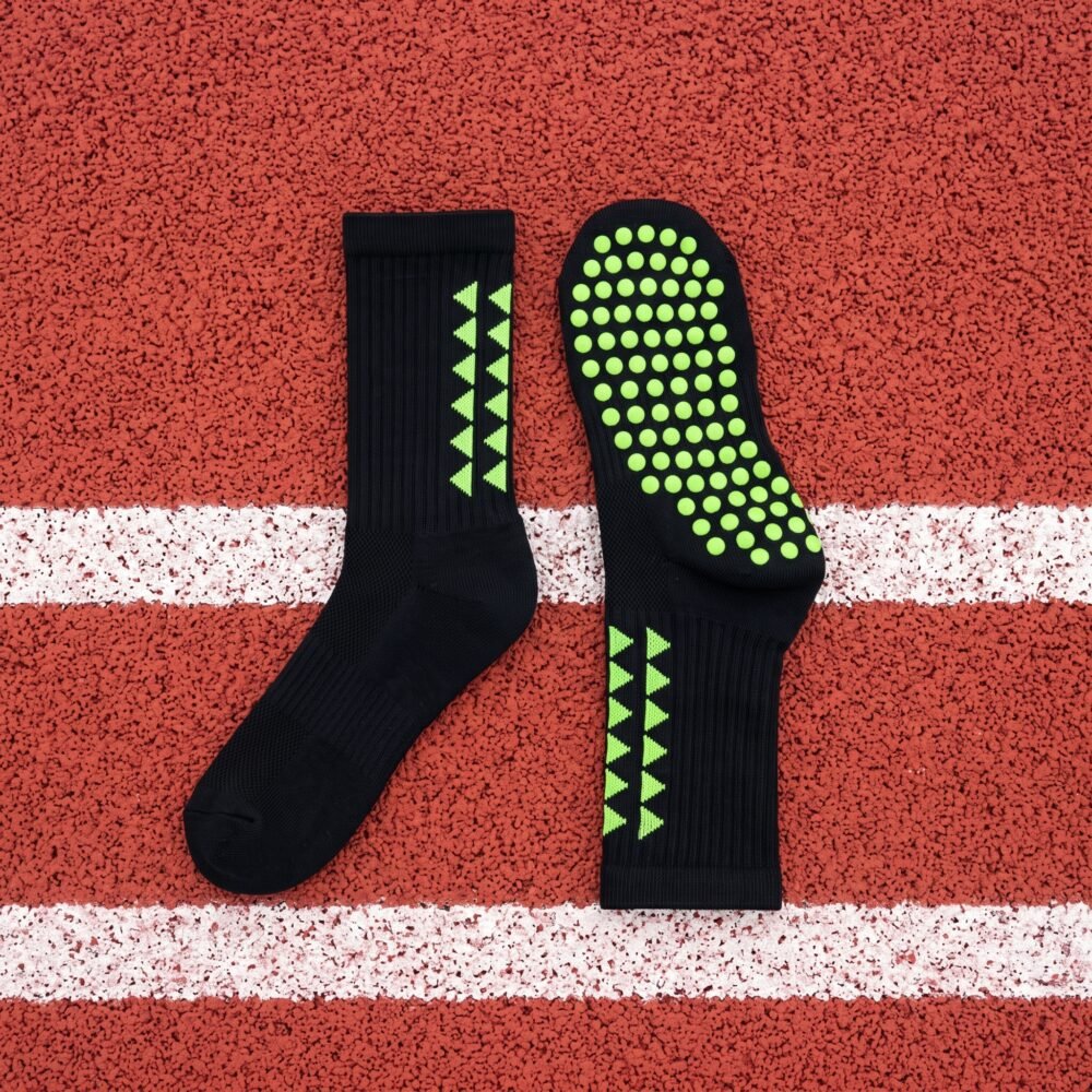 Black grip socks with lime green non-slip traction dots worn on a running track