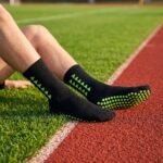 Black grip socks with lime green non-slip traction dots worn on a running track