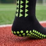 Black grip socks with lime green non-slip traction dots worn on a running track