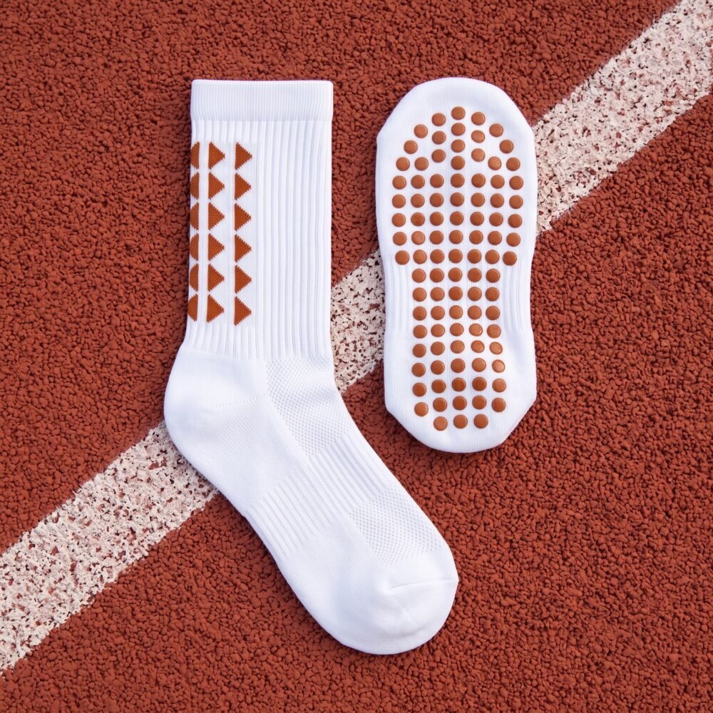 White Grip Socks with brown geometric accents and non-slip sole traction dots worn on an outdoor running track
