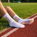 White Grip Socks with brown geometric accents and non-slip sole traction dots worn on an outdoor running track