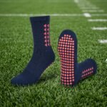 Navy blue Grip Socks with coral geometric accents and non-slip traction dots worn on a soccer field