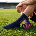 Navy blue Grip Socks with coral geometric accents and non-slip traction dots worn on a soccer field