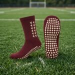 Maroon Grip Socks with cream geometric design and non-slip sole grip worn on a sports field