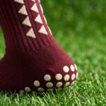 Maroon Grip Socks with cream geometric design and non-slip sole grip worn on a sports field