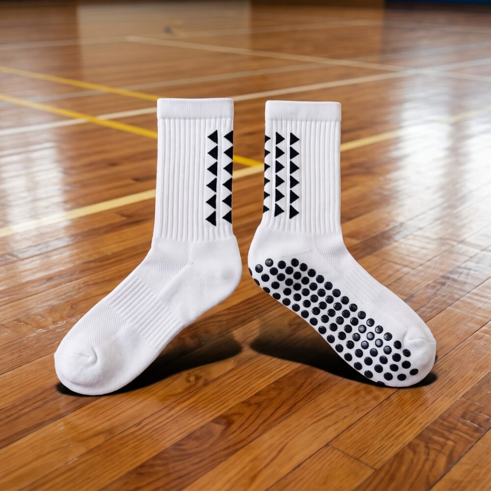 White Grip Socks with black geometric accents and anti-slip grip dots worn on an indoor sports court