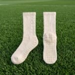 Cream Grip Socks with non-slip traction dots worn on artificial football field