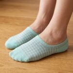 A pair of mint green no show socks with a grey gingham pattern laid flat against a white background.