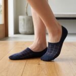 A pair of dark navy blue no show socks featuring a copper windowpane grid pattern across the top, laid flat against a clean white background.