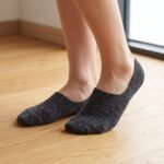 A pair of charcoal grey no show socks featuring multi-colored speckles, laid flat against a clean white background.