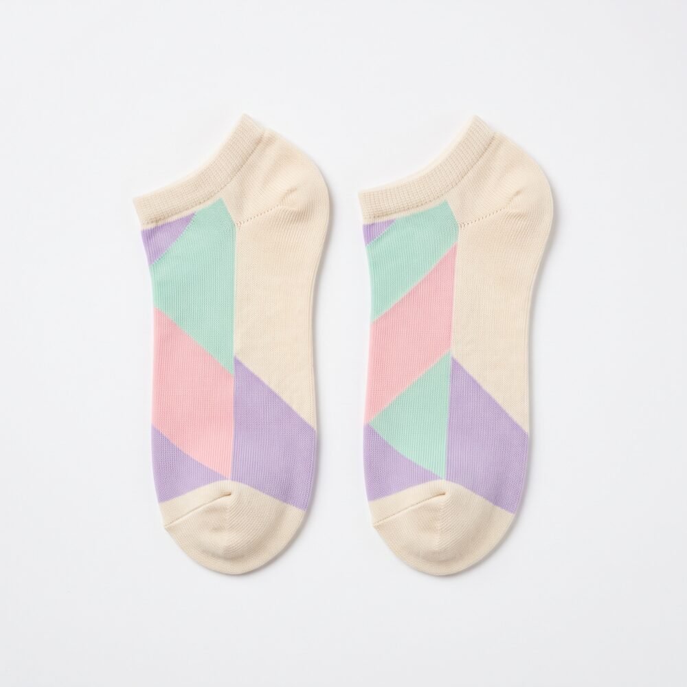 A close-up of a person's feet wearing ultra-low cut no show socks with a pastel pink, lavender, and mint green geometric pattern, standing tiptoe on a wooden surface.
