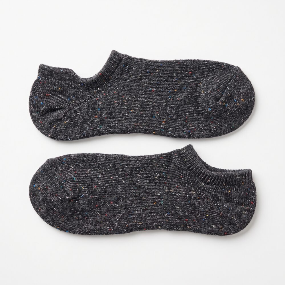 A pair of charcoal grey no show socks featuring multi-colored speckles, laid flat against a clean white background.