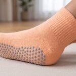 Peach Pilates Socks with gray non-slip grip dots displayed on a yoga mat