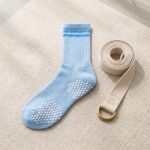 Light blue Pilates socks with white non-slip grip dots worn during an indoor workout