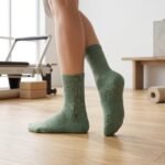 Sage green Pilates socks with non-slip grip dots worn during an indoor Pilates workout