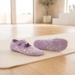 Pilates socks with cross strap design and non-slip grip soles on a Pilates mat