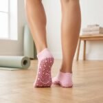 Pink Pilates socks with red non-slip grip dots worn during an indoor workout