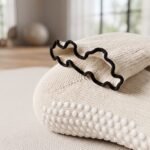 White Pilates socks with non-slip grip dots and scalloped cuffs worn during a Pilates workout