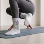Woman wearing gray women’s crew grip socks with purple floral embroidery and non-slip grip soles during a workout
