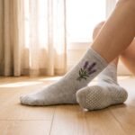 Woman wearing gray women’s crew grip socks with purple floral embroidery and non-slip grip soles during a workout